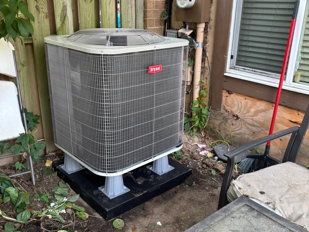 Carrier condenser on a raised pad beside a fence