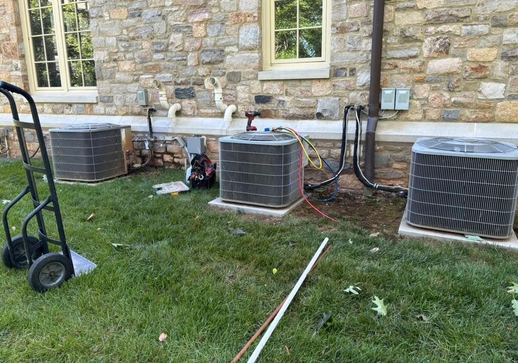 Three condensers along a stone wall during a multi-unit replacement