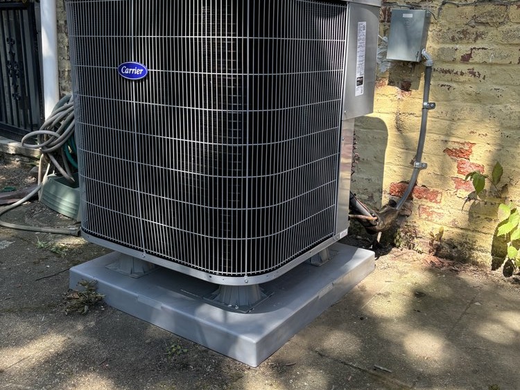 Carrier outdoor unit on a level pad against a brick wall